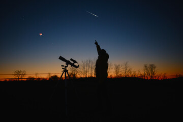 Wall Mural - astronomer looking at the starry skies and crescent moon with a telescope.