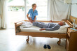 © Robert Kneschke - Nurse lifting legs of elderly man lying in bed