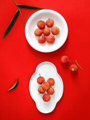 Canvas Print - Top view of Lychee tropical fruit on a white plate on a red surface