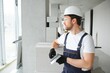 © Serhii - Portrait of a young foreman in uniform standing on a construction site indoors near a stepladder.