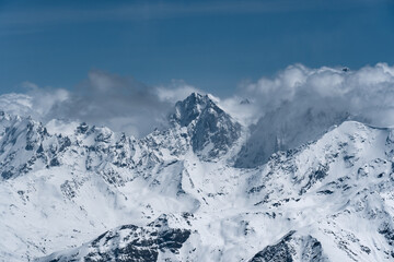 Wall Mural - Alpine landscape with peaks covered with snow and clouds