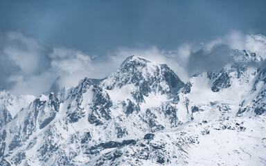 Wall Mural - Alpine landscape with peaks covered with snow and clouds