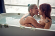A young sexy tattooed lesbian couple kissing while enjoying a bath in the bathroom with a money in the water. Love, relationship, luxury, bath, lgbt
