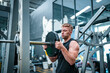 © FotoArtist - Male athlete exercising in the gym, lifting weights, pulling joints.