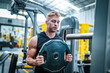 © FotoArtist - Male athlete exercising in the gym, lifting weights, pulling joints.