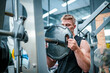 © FotoArtist - Male athlete exercising in the gym, lifting weights, pulling joints.