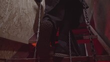 The Legs Of The Prisoner In Chains Closeup. Feet Step Upstairs. Red Light. Abandoned House. High Quality FullHD Footage With Slow Motion. 