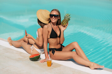 Wall Mural - two beautiful woman with cocktail sitting near infinity pool and looking to sea and horizon