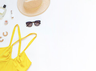 Wall Mural - Summer yellow dress with straw hat and sunglasses on the white background. Top view. Copy space	