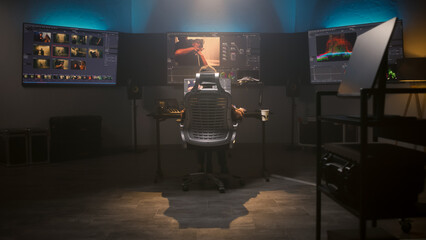 Fototapete - The editor works in studio on computer, edits video, makes color correction for movie post production. Big screens showing color grading program interface with film footage, RGB graphic and levels.