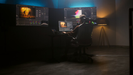 Fototapete - Female editor works in studio on computer using color grading control panel and professional video editing software. Color correction for film post production. Big screens with RGB graphic and levels.