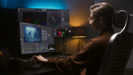 The editor works in studio on computer, uses color grading control panel, edits video, makes color correction for movie. Big screens showing program interface with film footage, RGB graphic and levels