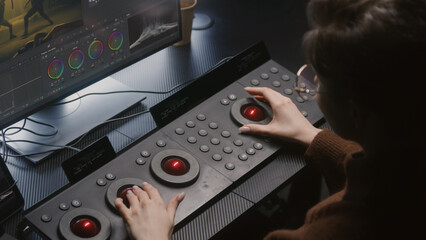 Fototapete - Female editor uses digital color grading control panel. Colorist makes video or photo color correction on computer in studio. Footage and program interface with RGB color wheels and levels on monitor.
