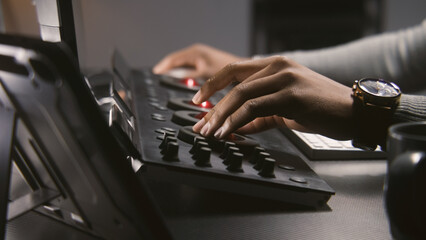 Fototapete - Hands close up of African American colorist working by color grading control panel in studio with modern design. Film editor makes colour correction for video post production. Professional equipment.