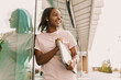© Volodymyr - Happy positive smiling african american woman hipster standing outside hold laptop leaned against the glass wall. Young entrepreneur freelancer student businesswoman looking aside