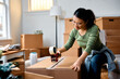 © Drazen - Asian woman taping carboard boxes while relocating into new home.