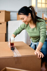 Wall Mural - Happy Asian woman packing carboard boxes while moving out of her home.