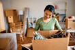 © Drazen - Happy Asian woman unpacking her belongings while relocation in new home.