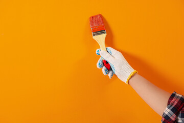 Wall Mural - Designer painting orange wall with brush, closeup. Space for text