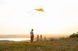 © Юля Шевцова - Happy man and children, father and sons, with kite in nature at sunset