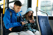 © Oleksandra - two teenagers in blue clothes sit on bus Canada Vancouver hoods autumn winter spring tracksuits use a mobile phone search for geolocation travel travelers real life