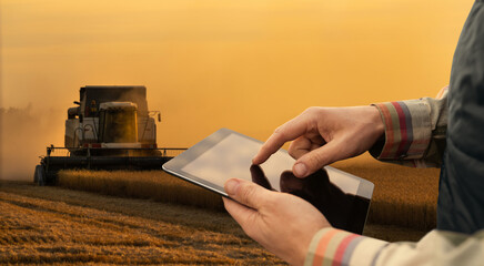 Sticker - Farmer with digital tablet on a background of harvester. Smart farming concept.