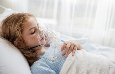 portrait of little girl suffering from pneumonia lying in hospital bed with oxygen mask. teenage kid