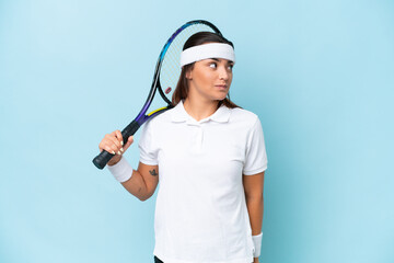 Poster - Young tennis player woman isolated on blue background looking to the side