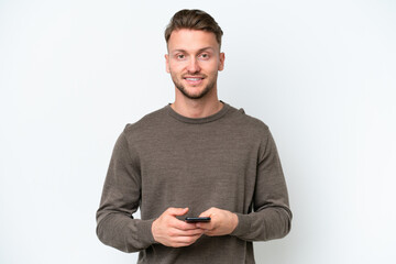 Wall Mural - Young blonde caucasian man isolated on white background sending a message with the mobile