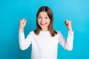 Wall Mural - Photo portrait of cute little girl fists excited celebrate lottery good news wear trendy white outfit isolated on blue color background