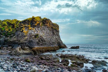 Beautiful view of a rocky shore with cliff under the cloudy sky