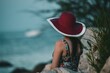 Beautiful shot of a woman with a red hat looking at the sea