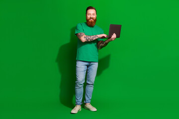 Wall Mural - Full length photo of confident attractive man wear t-shirt working modern gadget isolated green color background