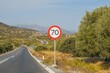 © Lucija Kanižaj/Wirestock Creators - 70 KM road sign on the roadside with line of greenery and mountain in the background