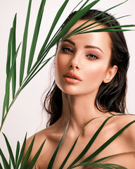 Wall Mural - young beautiful woman with green leaves near face and body. skin care beauty treatments concept. clo