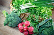 Healthy fresh organic food in springtime, variety of fresh vegetables in a wicker basket on a wooden table