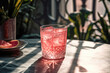 © ADDICTIVE STOCK - Generative AI illustration of glass of refreshing pink iced cocktail drink with slice of red grapefruit placed on marble table beside plants in cafe