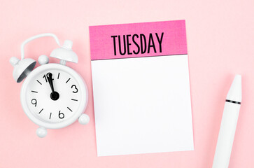 the blank note paper for tuesday and pen with alarm clock on pink color background for your text or 