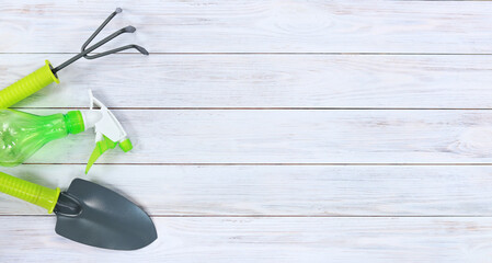 Shovel, rake and spray gun for gardening on a wooden background. Gardening tools on light wooden table background