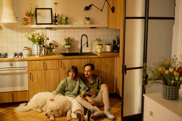 Young couple sit relaxed together with a cute dog on kitchen at home. Home coziness and domestic lifestyle concept