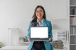 © wichayada - Happy asian business woman holding laptop with blank screen stands in a modern office looking at the camera and smiling friendly