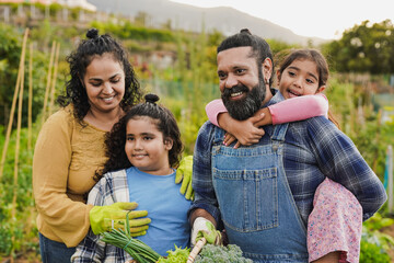 happy indian family gardning together - parents and children having fun outdoor - harvest, garden an