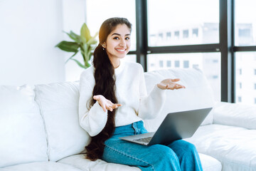 successful startup. cheerful young business woman sitting on white couch in spacious bright office d