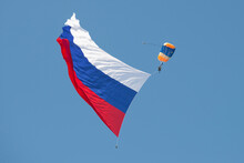 Skydiver With A Large Russian Flag In A Blue Cloudless Sky