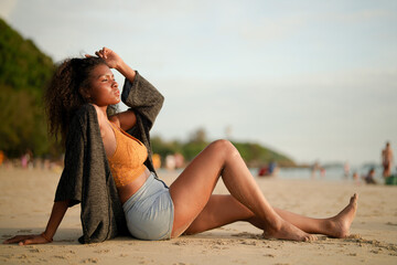 Wall Mural - African woman sit on the beach. Portrait sexy African lady travel ping and relaxing in the summer with tropical nature.