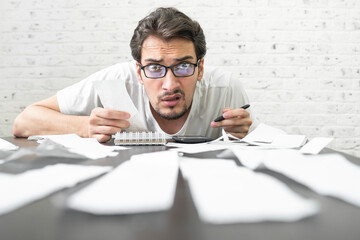 Wall Mural - Close up of unhappy man sitting at the table, stressed and confused by calculate expense from invoice or bills, have no money to pay mortgage or loan. High prices and spending money concept