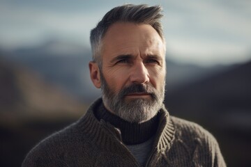 Canvas Print - Portrait of a handsome mature man with gray beard and mustache wearing a woolen sweater in the mountains