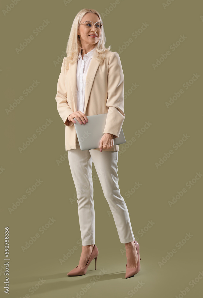 Mature woman with laptop on green background