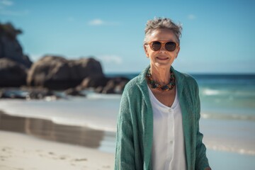 Poster - Portrait of smiling senior woman standing at beach on a sunny day