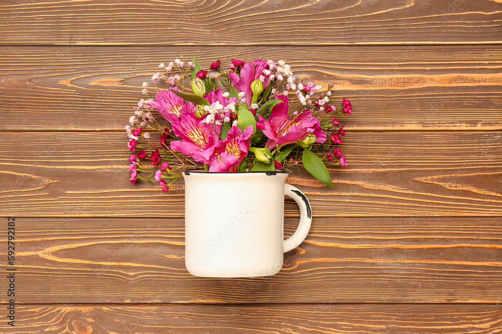 Cup with beautiful flowers on wooden background